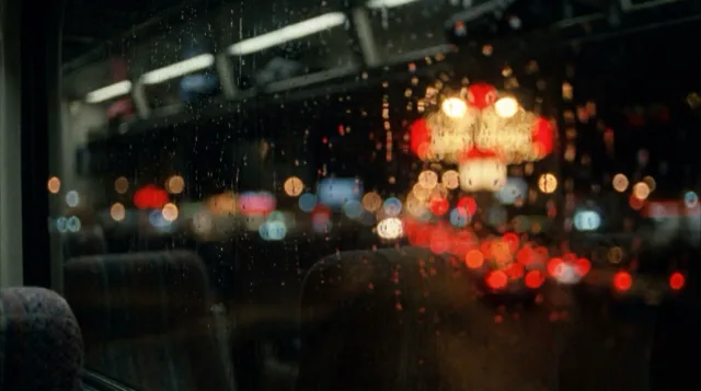 A city's night lights through a coach window, all soft discs of colour.