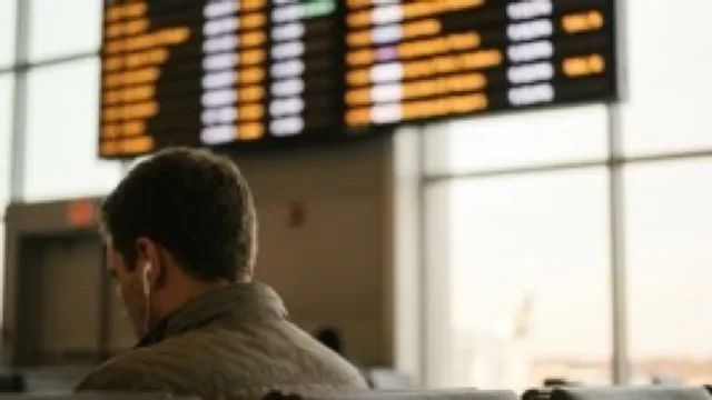 A departure board as glowing bars, out of focus; an earbud in the foreground.